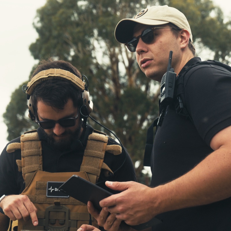 Two colleagues heads-down over a rugged tablet on a range.