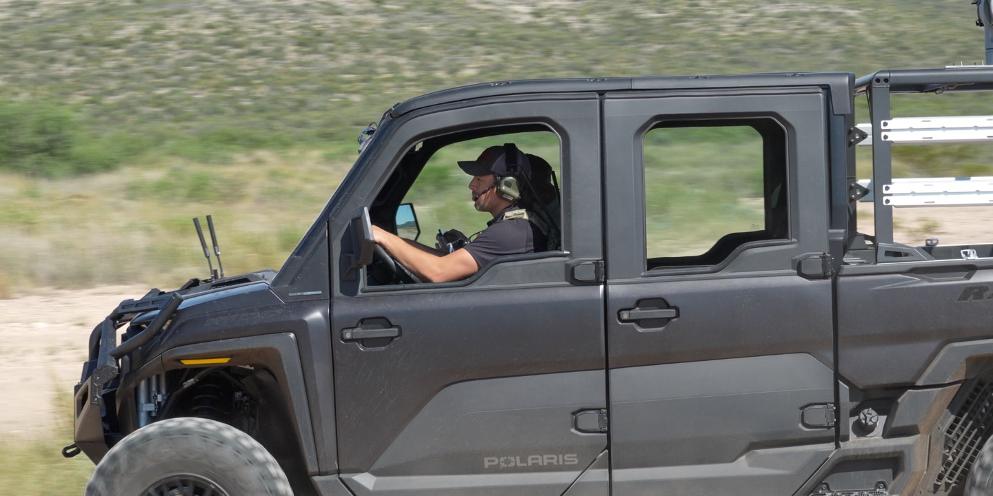 A colleague driving a ground vehicle across a desert track.