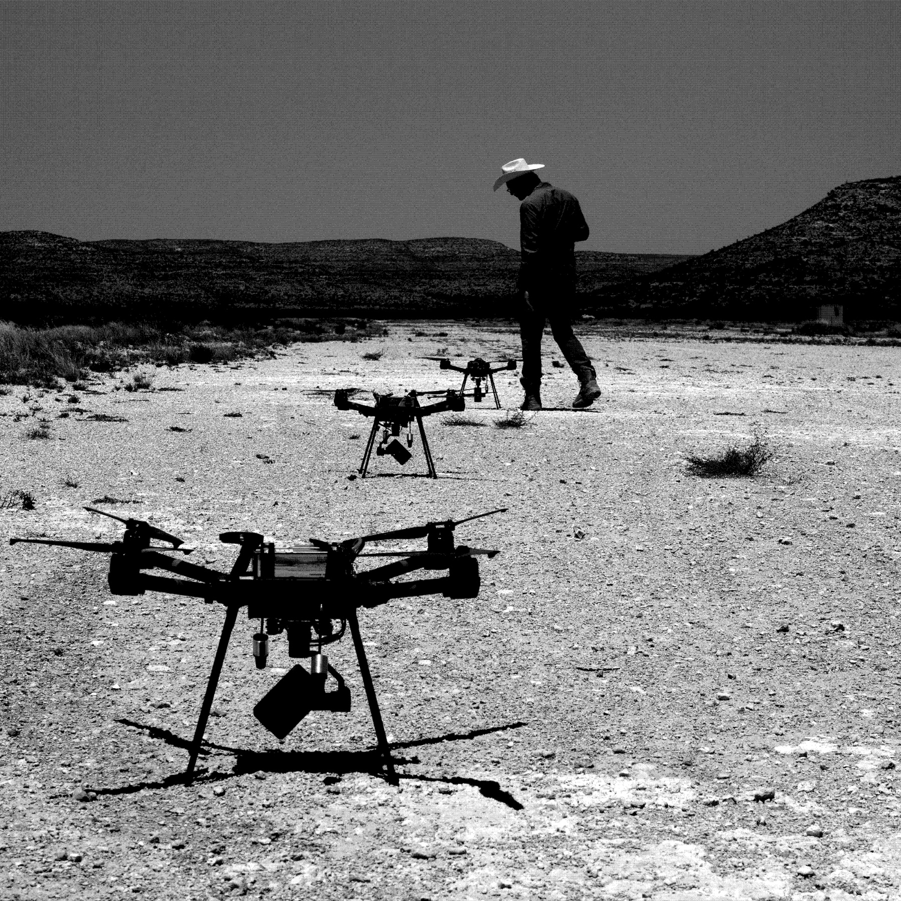 Two drones on a desert pad, an operator walking out beyond them.
