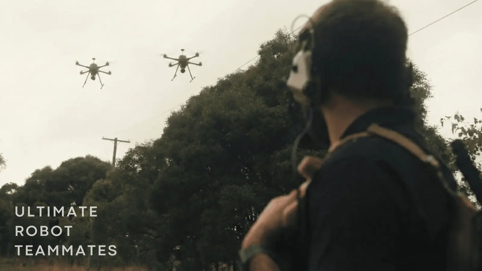 An operator in the field watching two drones overhead, with the words Ultimate Robot Teammates.