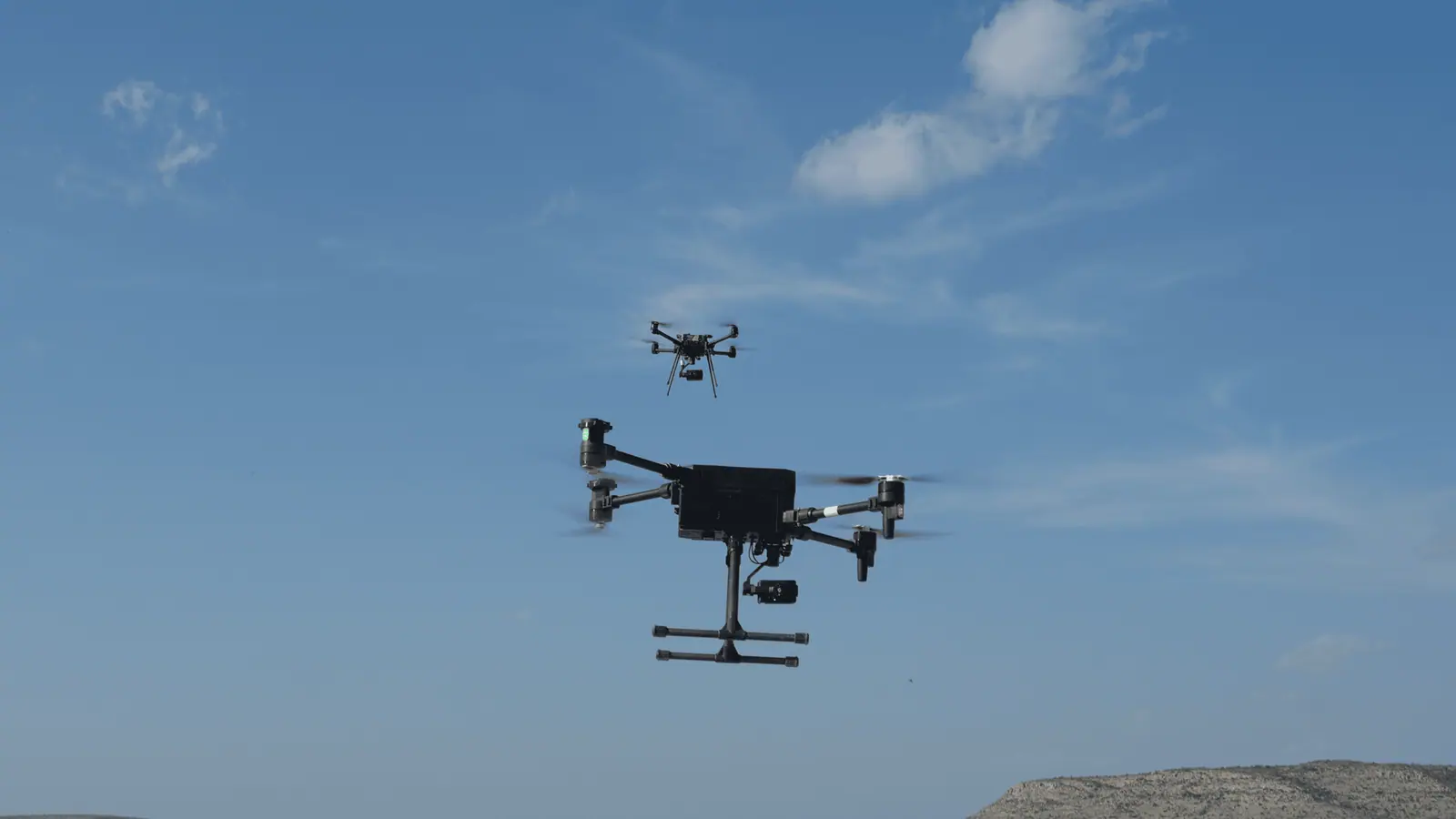 Two Breaker quadcopters in flight against a blue sky.