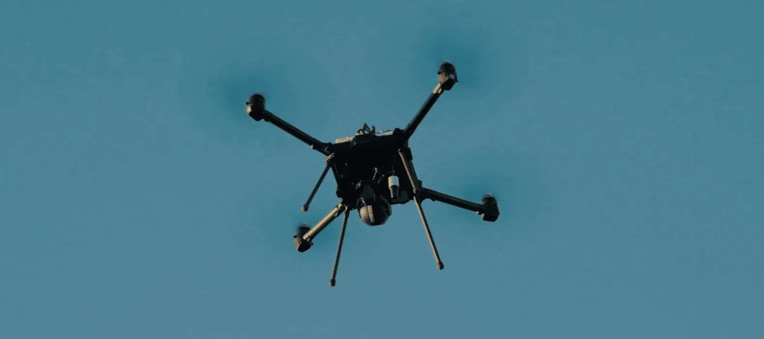 A quadcopter in flight against a clear sky.