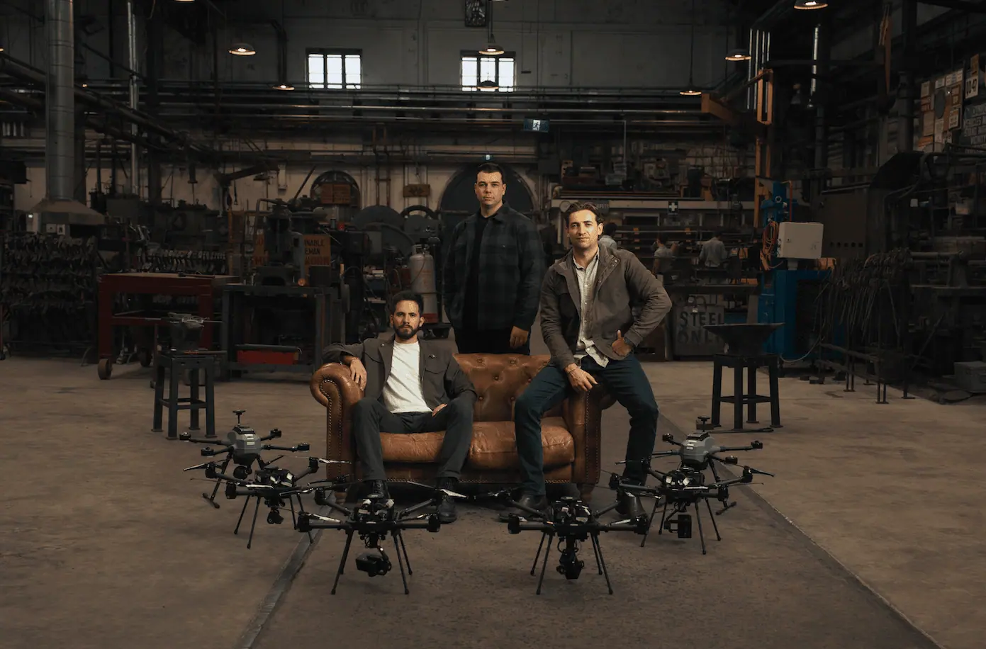 Breaker's founders in a workshop, surrounded by six large multirotor drones.